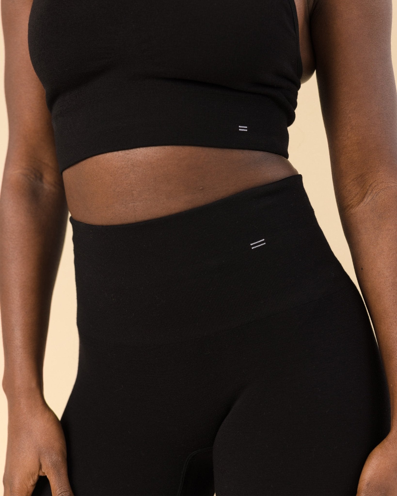 Detail photo of a woman wearing a Merino sports bra and compressive Merino leggings. Close-up highlights the supportive waistband designed for comfort without restriction.