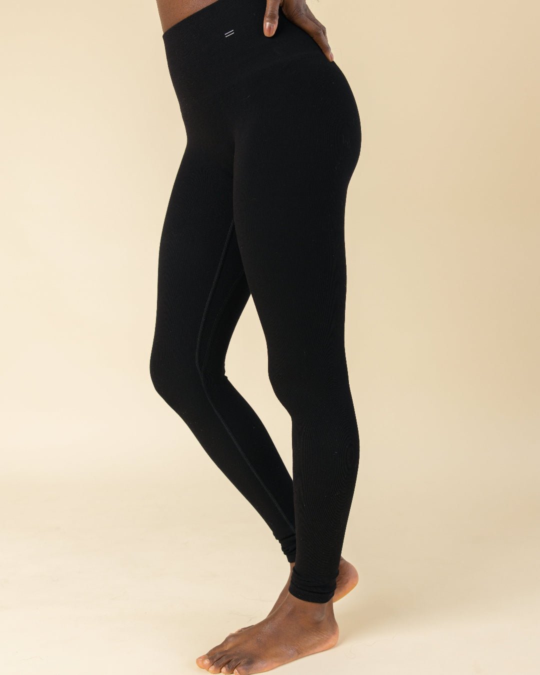 Woman standing with hands on her hips in black compression leggings made of Merino Wool by BRANWYN.