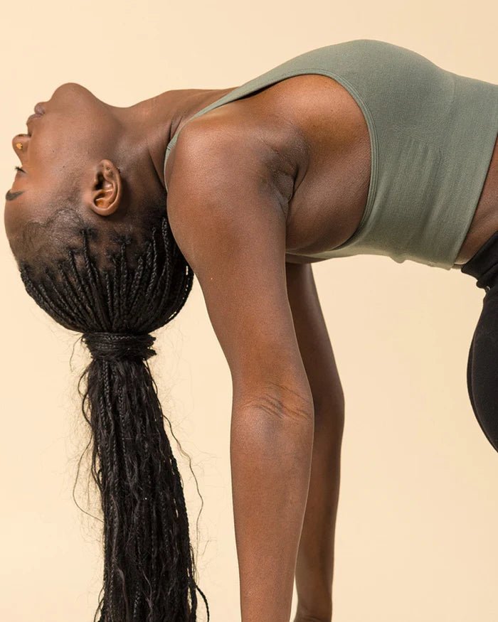 Yoga stretching in green Merino sports bra, BRANWYN Essential Racerback Sports Bra. Compressive seamless Merino fabric hugs the body while staying breathable.