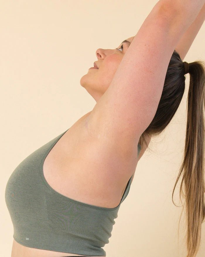 Side view of model stretching in Merino Racerback Sports Bra by BRANWYN in agave green, ideal for yoga, pilates, gym workout bra.