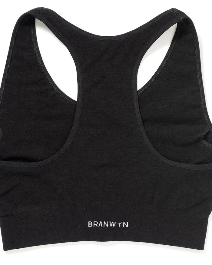 Flatlay of the BRANWYN Racerback Sports Bra in black. Seamless Merino compression bra with sleeves for pads designed for exercise.