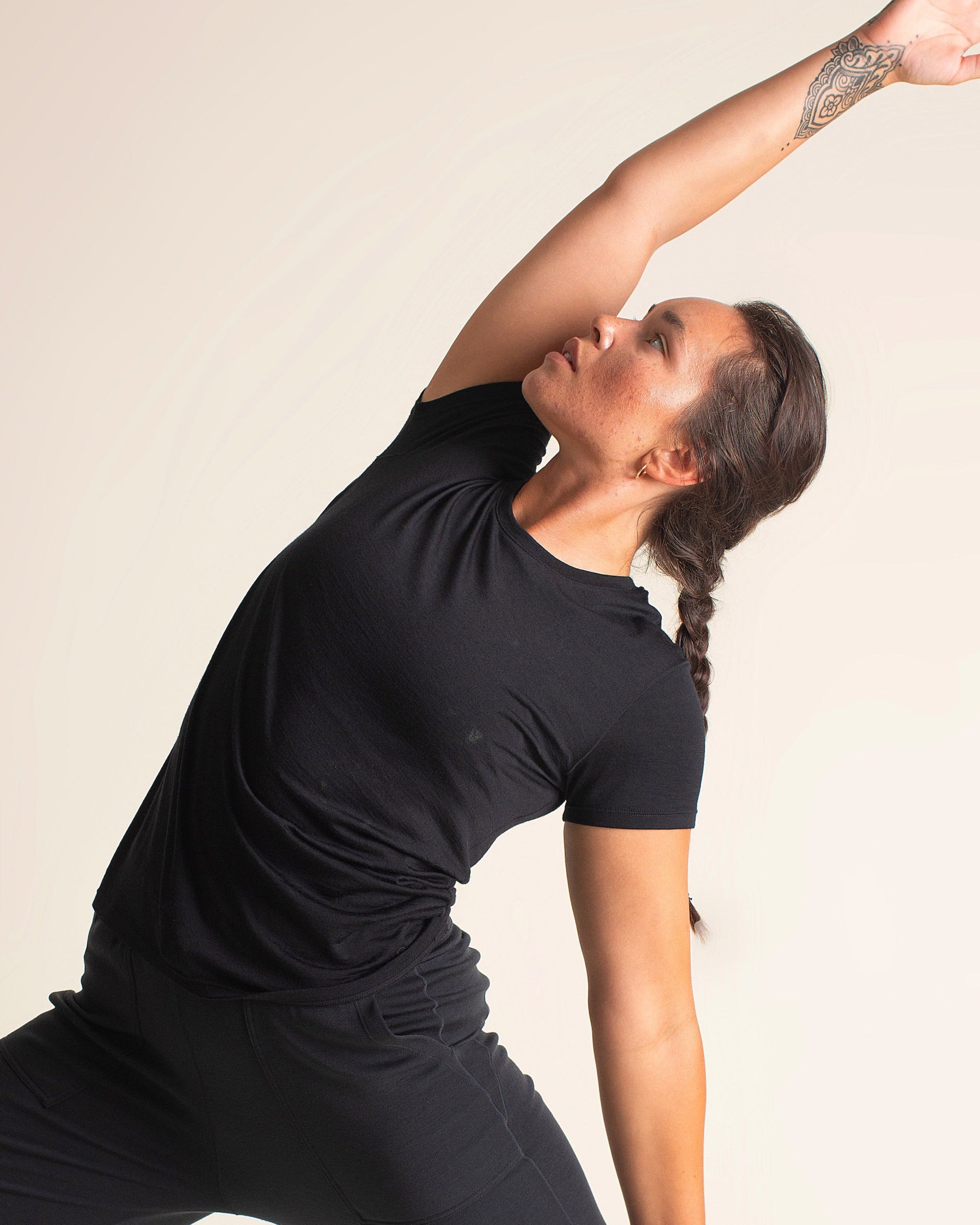 Woman wearing BRANWYN Women's Merino Wool Black Short Sleeve Tee in a yoga pose