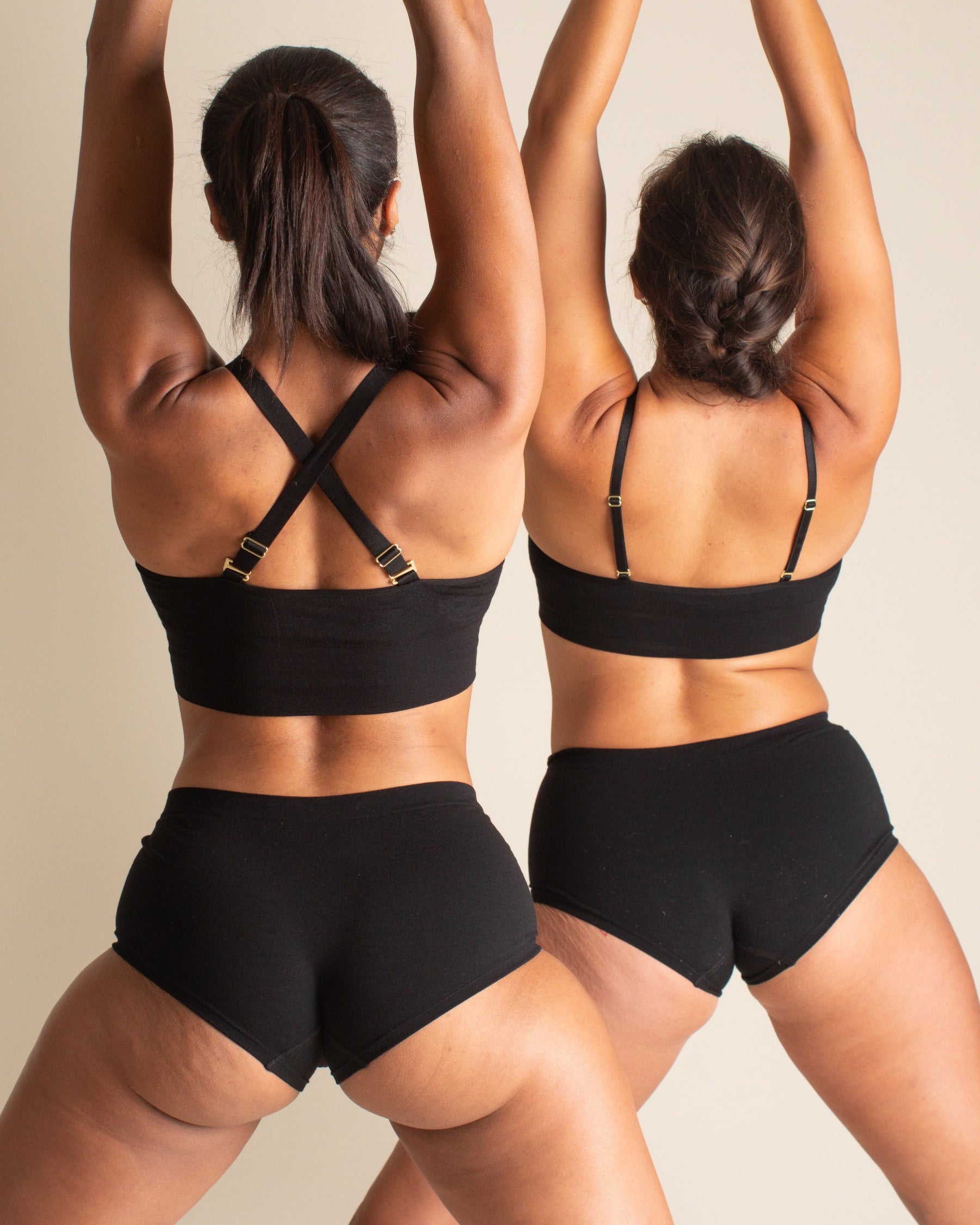 Two women doing yoga to show how the back of BRAWNYN women's seamless Merino wool Boyshorts underwear in Black looks on different body types. Great for skiing, travel underwear, and the best hiking underwear.