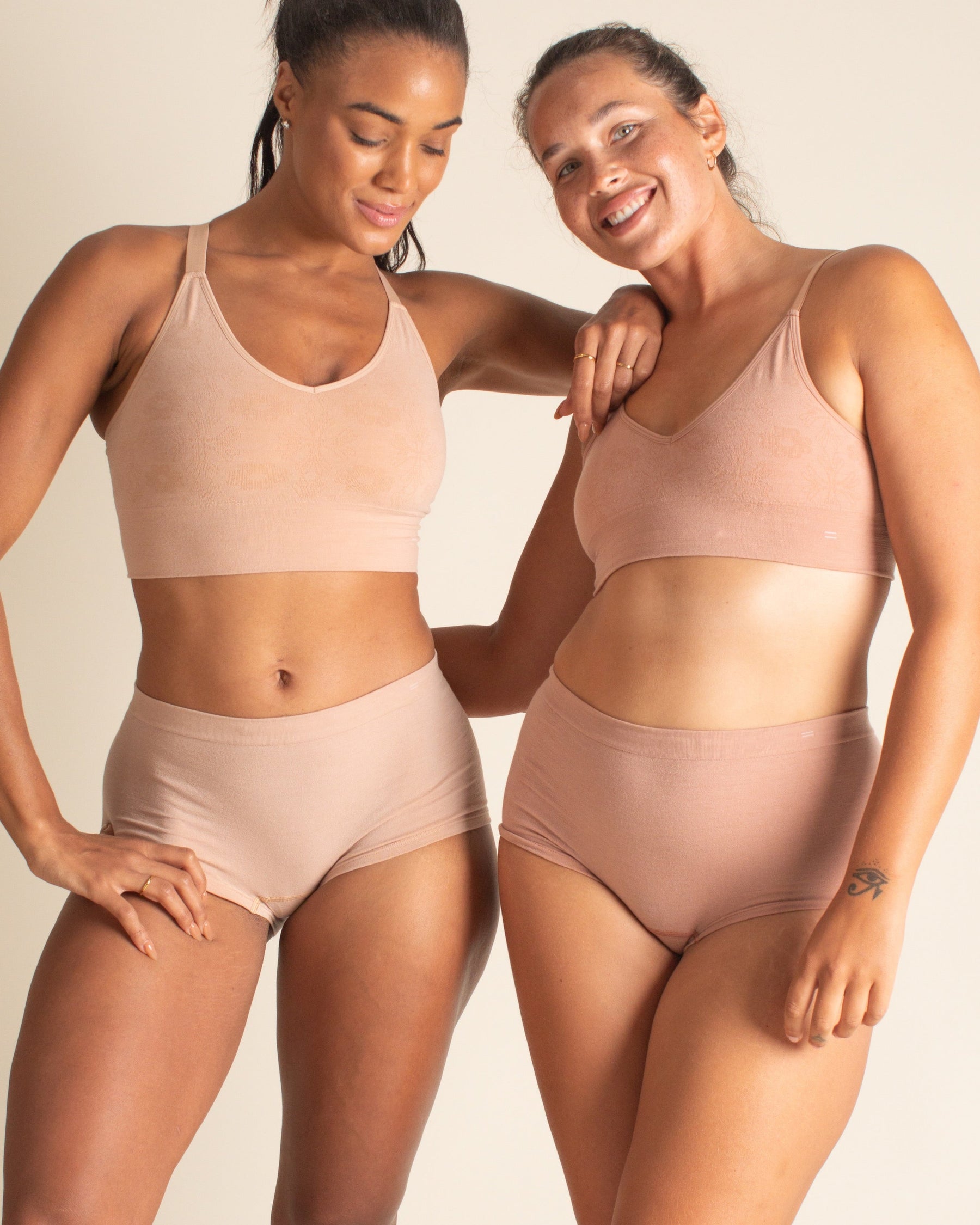 2 women: one is wearing BRAWNYN women's seamless Merino wool Boyshorts underwear and Busty Bra in Light Nude. The other is wearing BRAWNYN women's seamless Merino wool Boyshorts underwear and Busty Bra in Warm Nude.Great for skiing, travel underwear, and the best hiking underwear.