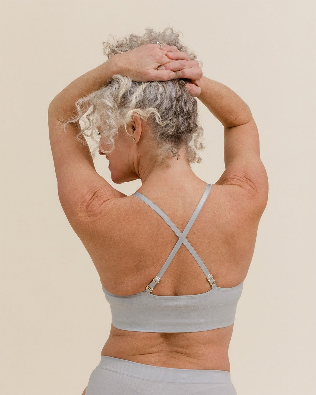 Woman wearing BRANWYN Essential Bralette in Luna Grey, adjustable Merino straps crossed for support.