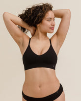 Front view of woman stretching in BRANWYN Essential Bralette in black, soft breathable Merino bralette.