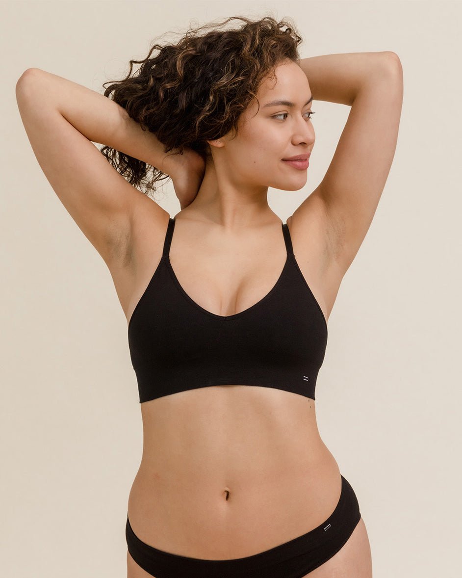 Front view of woman stretching in BRANWYN Essential Bralette in black, soft breathable Merino bralette.