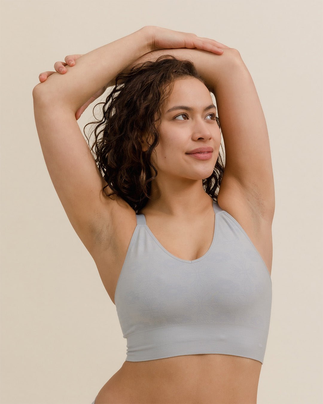 Woman stretching in BRANWYN Essential Busty Bra in Luna Grey, merino bralette designed for performance.