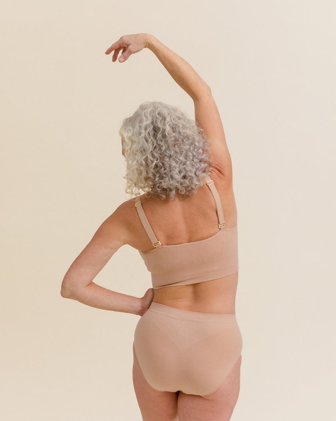 Model stretching in the comfiest Merino underwear set in light nude wearing BRANWYN's Essential Hipster high waisted seamless panties.