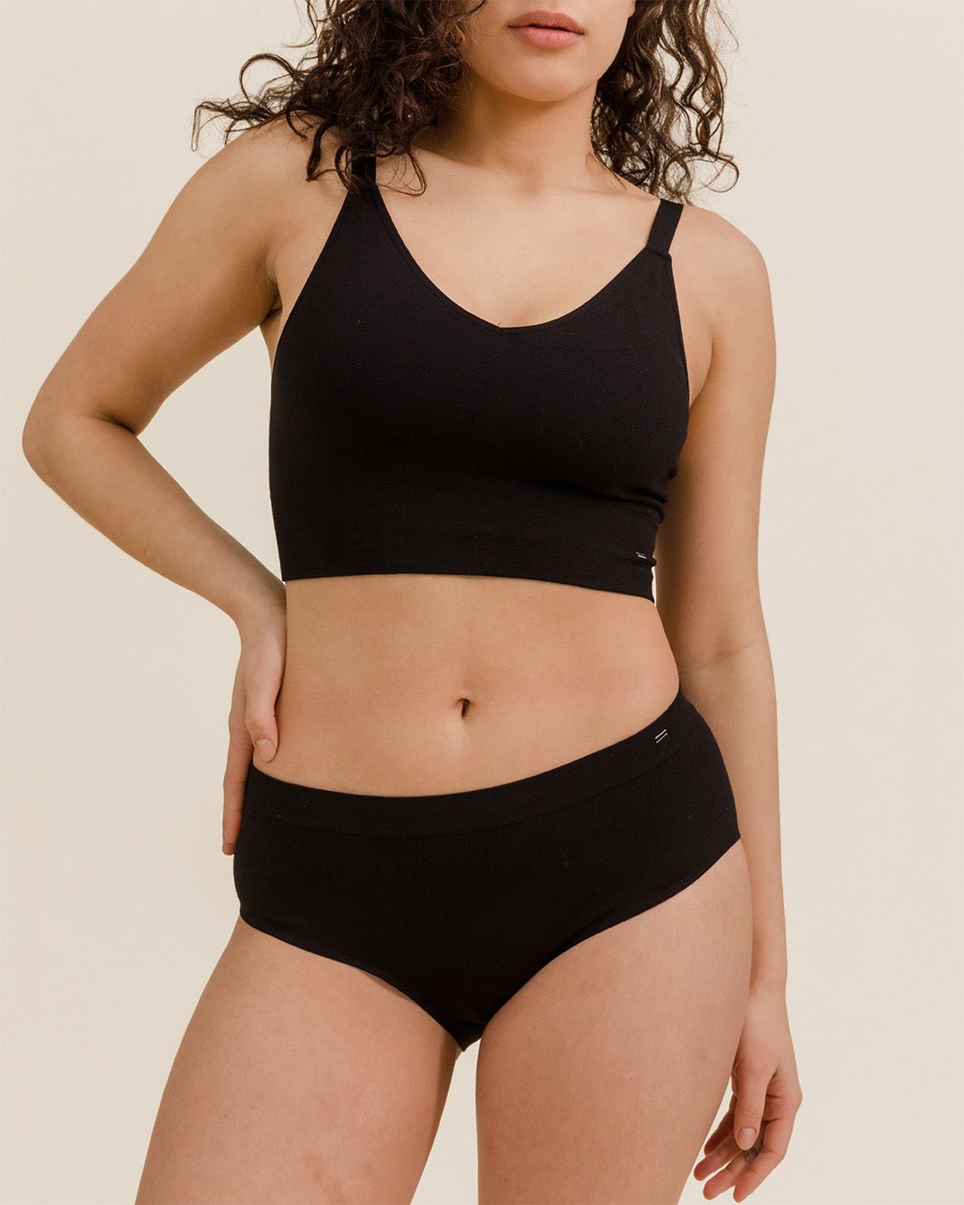 Woman standing in black Merino underwear, BRANWYN's Essential Hipster underwear known for it's breathability, comfort, and chafe free.