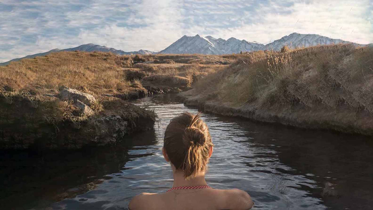 Women doing a cold plunge while swimming in a river in the mountains/