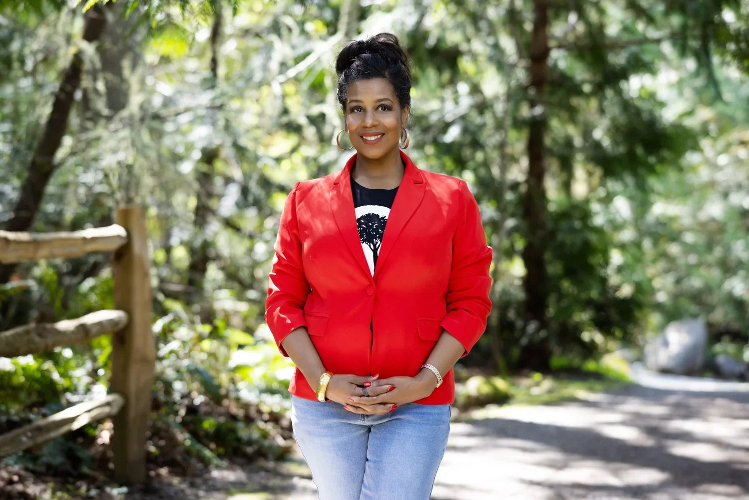Rue Mapp, founder of Outdoor Afro, posing in a red jacket in the forest.