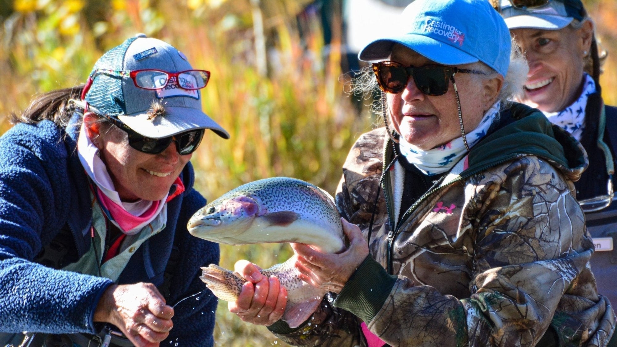 A group of woman on a casting for recovery retreat holding a fish they caught.