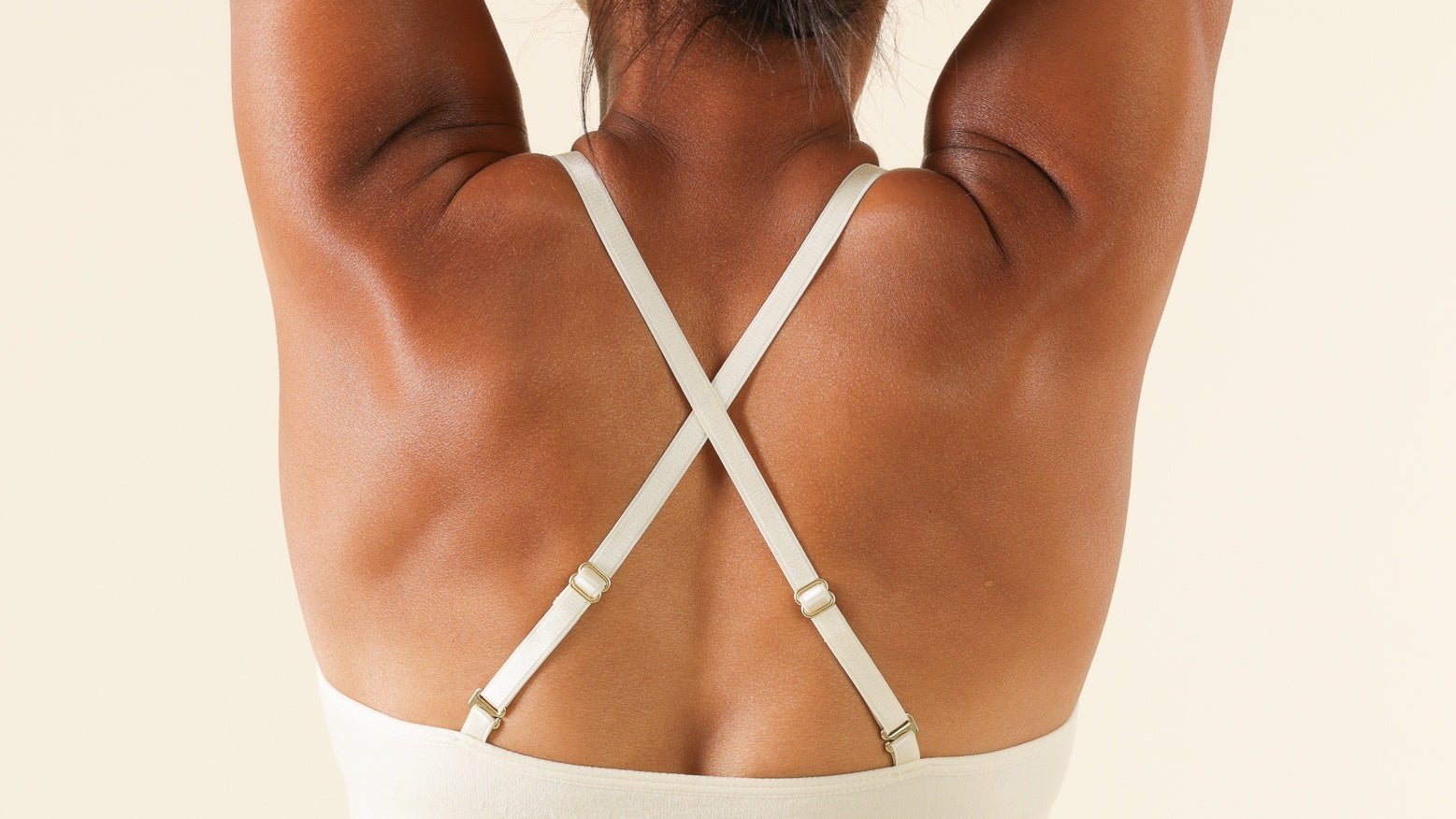 Woman stretching her arms upward while wearing a white Merino wool bra.