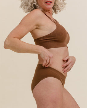 Woman in BRANWYN Essential Bikini underwear set, side view, made of breathable Merino wool for active women and outdoor adventures.