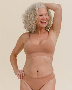 Woman smiling in BRANWYN Essential Bralette in Warm Nude, soft seamless Merino bralette.