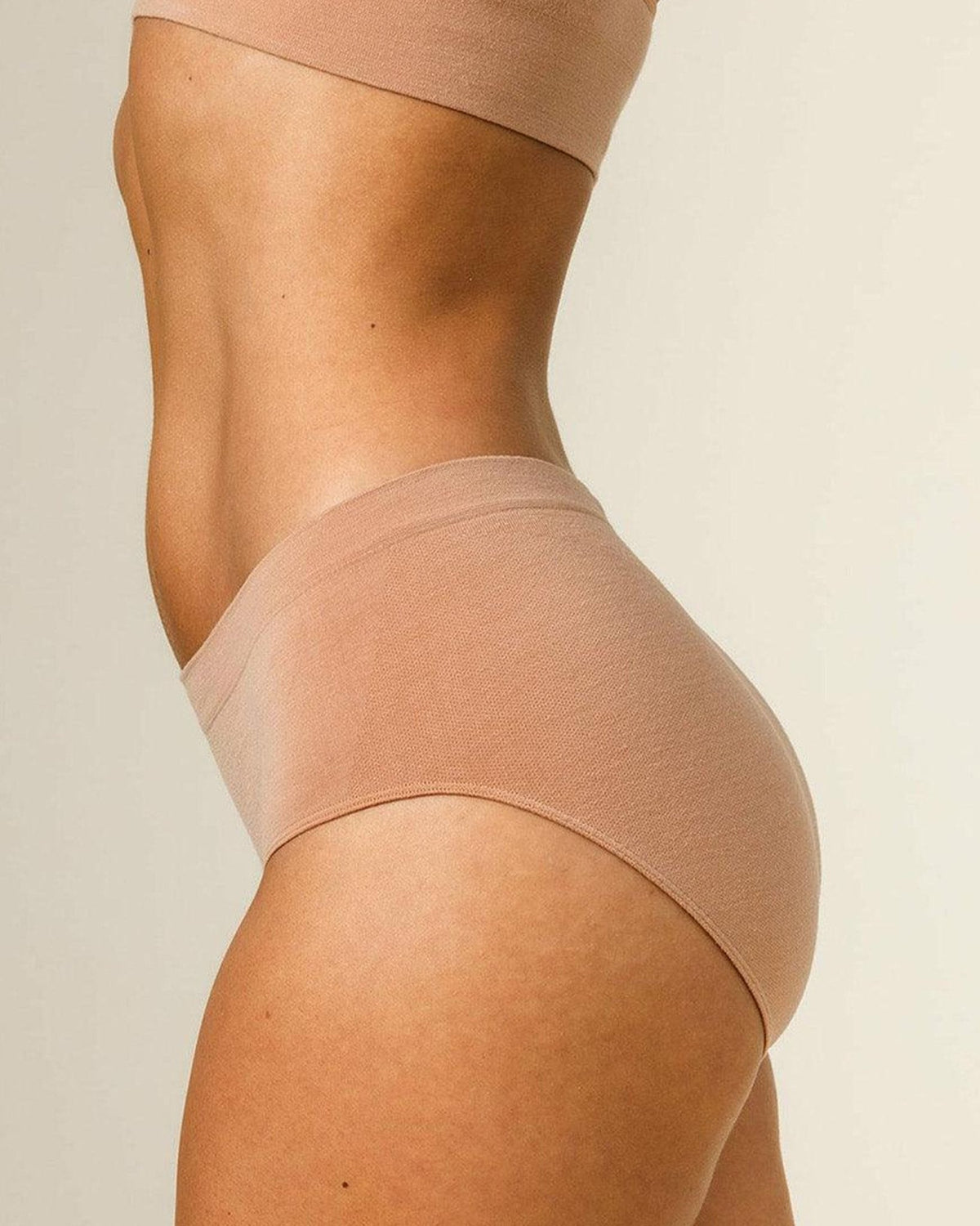 Side view of woman wearing BRANWYN Essential Merino wool underwear in light nude, moisture wicking merino underwear.