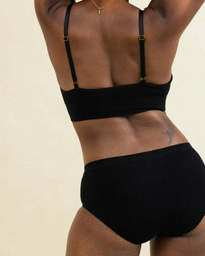 Woman stretching in seamless high waisted underwear set. BRANWYN's Essential Hipster in black, seamless Merino underwear.