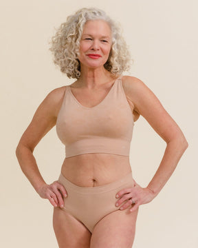 Model standing in BRANWYN Essential Hipster underwear. Light nude Merino panties that are breathable and eco-friendly.