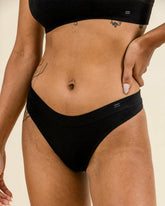 Woman wearing BRANWYN Merino Thong in black. Seamless, sustainable underwear with breathable comfort.