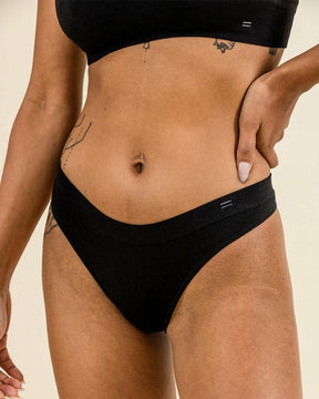 Woman wearing BRANWYN Merino Thong in black. Seamless, sustainable underwear with breathable comfort.