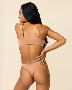 Back view of woman in Merino bralette and thong underwear set in warm nude by BRANWYN. Best thong for hiking and outdoor adventure.