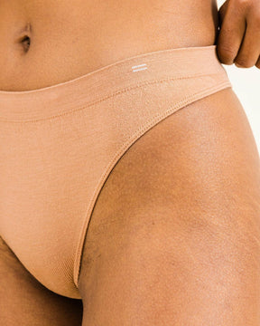 Detail of BRANWYN seamless thong in warm nude with equal sign logo. Super soft Merino wool underwear that stretches and moves with you.