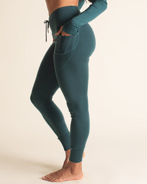 Woman wearing a teal athletic outfit on a beige background