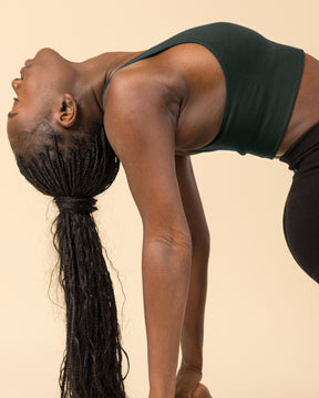 BRANWYN Essential Seamless Merino Wool Racerback Sports Bra in Deep Willow on a Model Doing Yoga