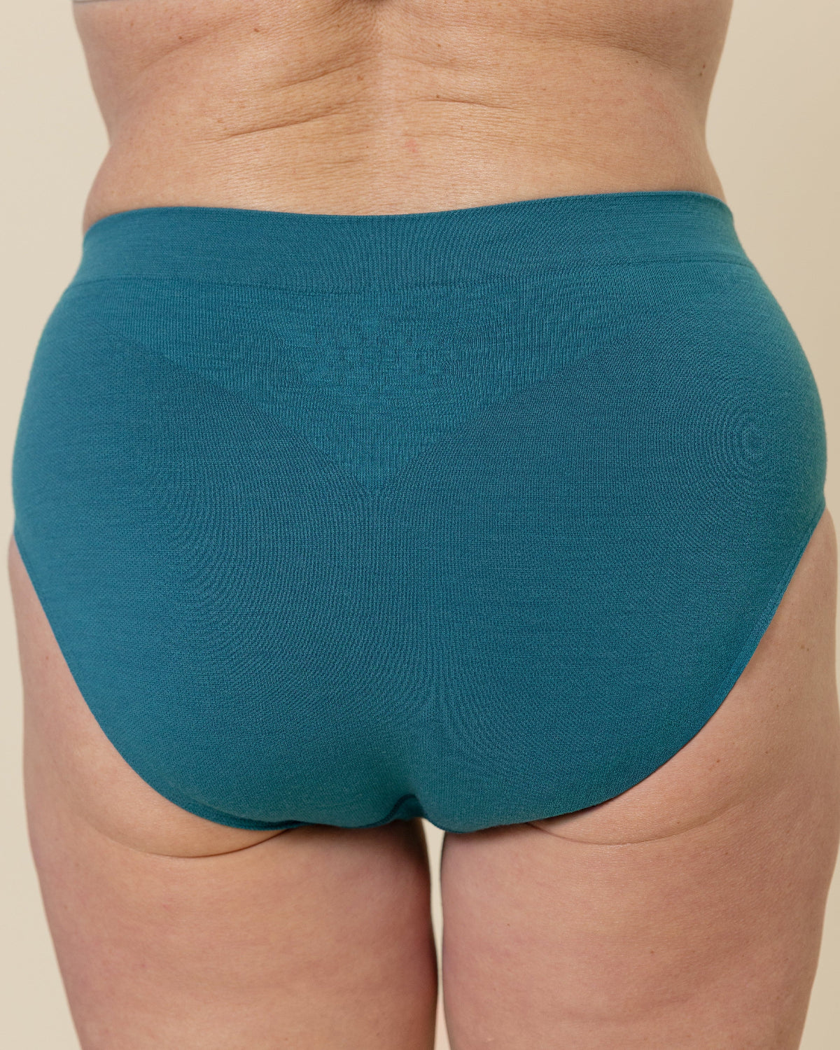 Back view of a model wearing BRANWYN Sustainable Seamless Merino Wool Essential Hipster in Transformative Teal.