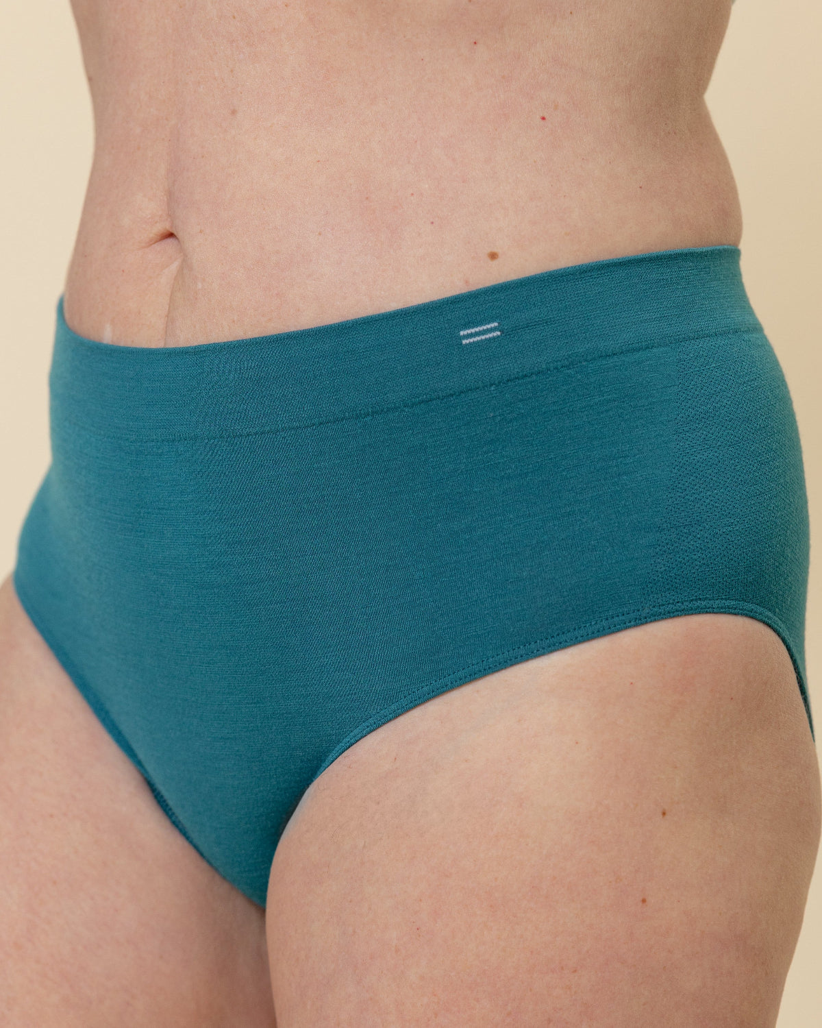 Side view of a model wearing BRANWYN Sustainable Seamless Merino Wool Essential Hipster in Transformative Teal.