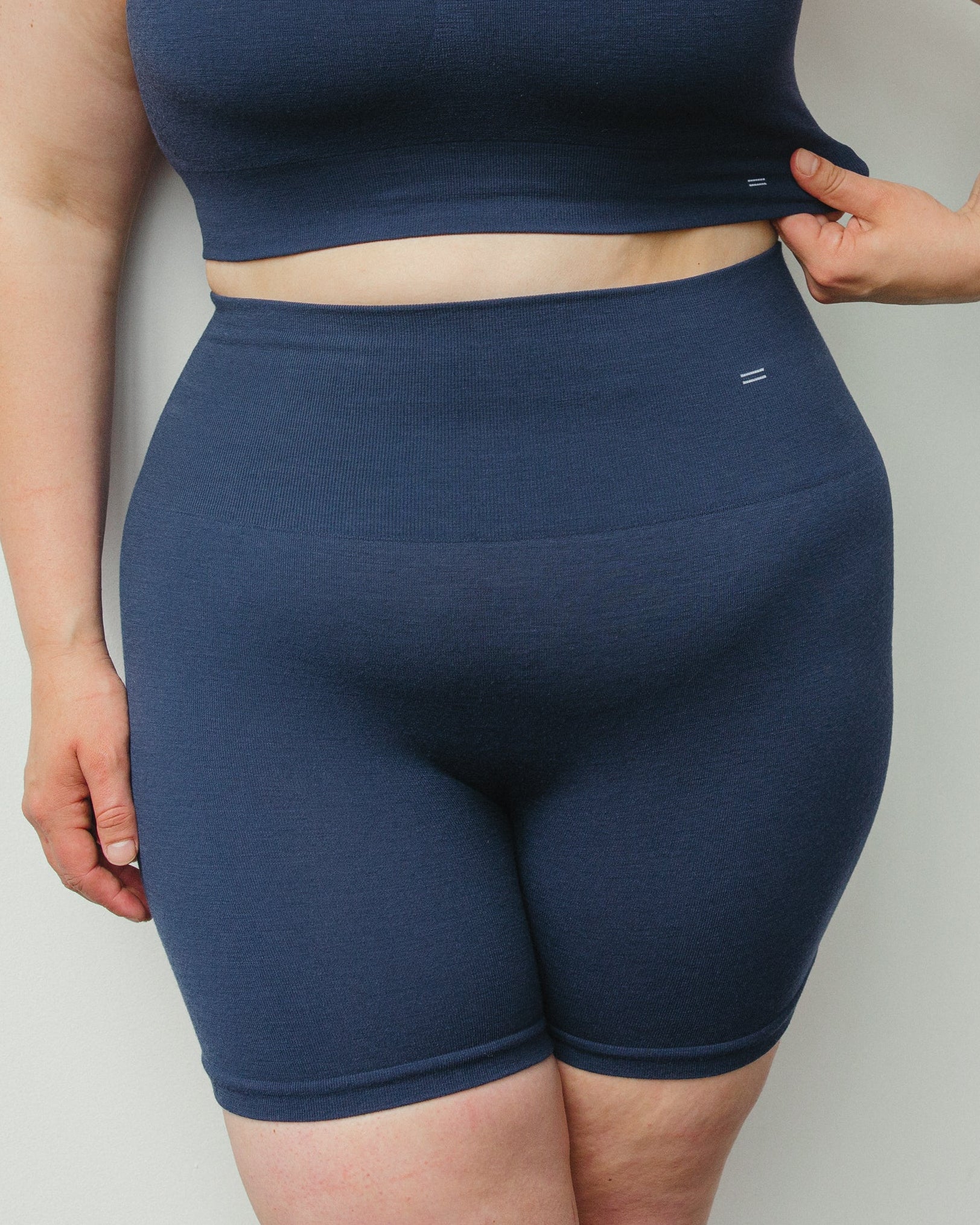 Woman wearing a navy blue athletic outfit against a plain background