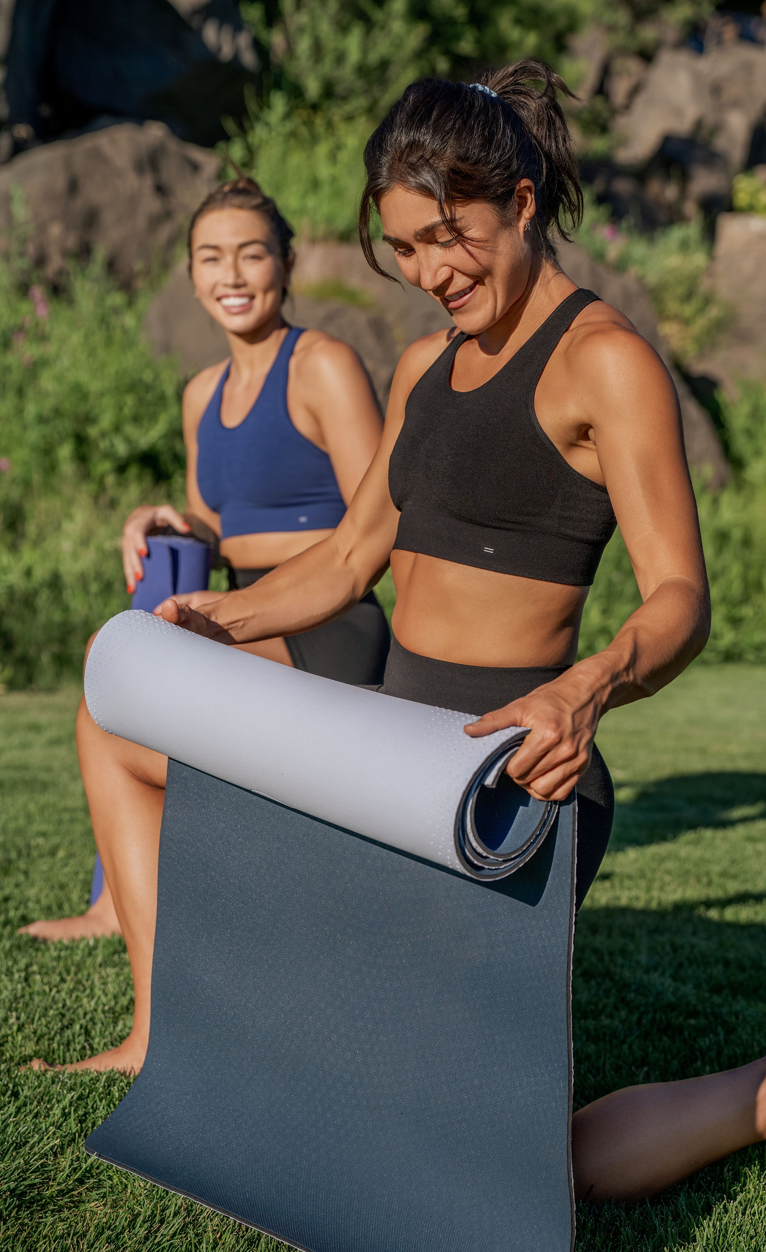 TWO WOMEN ROLLING UP YOGA MATS WEARING BRANWYN PERFORMANCE INNERWEAR SEAMLESS MERINO RACERBACK