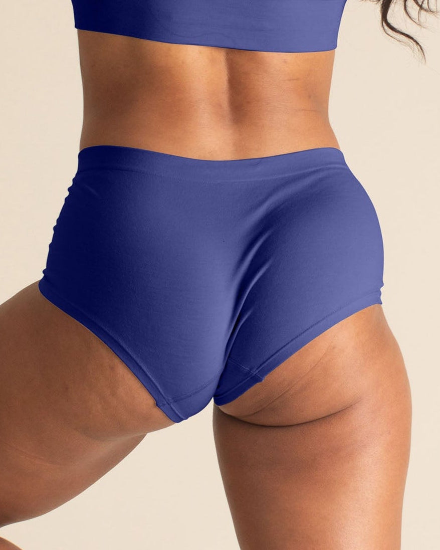 Woman wearing a BRANWYN Merino wool seamless future dusk boyshort set against a beige background.