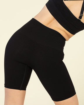Person wearing a black sports bra and shorts on a beige background