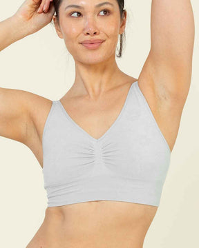 Woman wearing a light gray bikini set on a beige background
