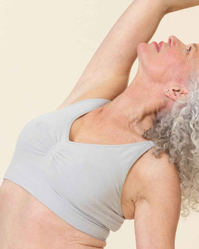 Woman in light blue athletic wear performing a yoga pose on a beige background
