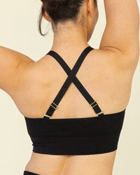 Person wearing a black sports bra and shorts on a beige background