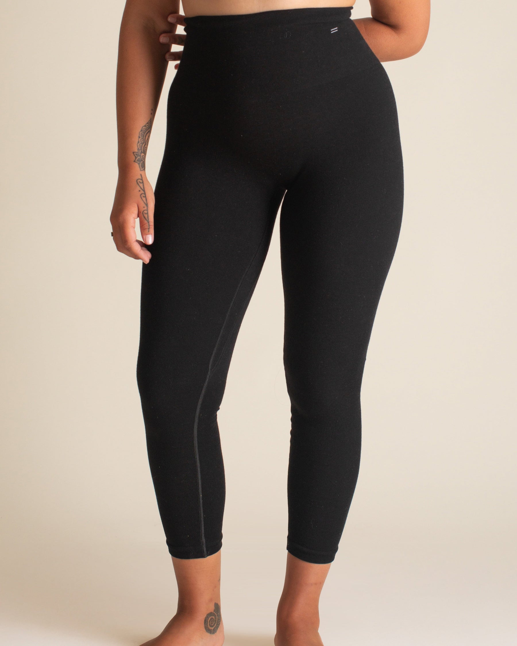 Person wearing black leggings on a plain background