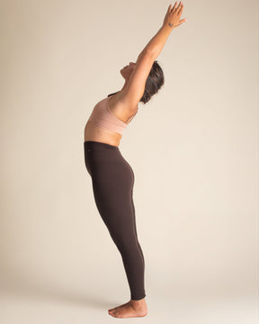 Woman in yoga mountain pose, wearing Mocha Brown Merino compression leggings that regulate temperature and keep you fresh from studio to trail.