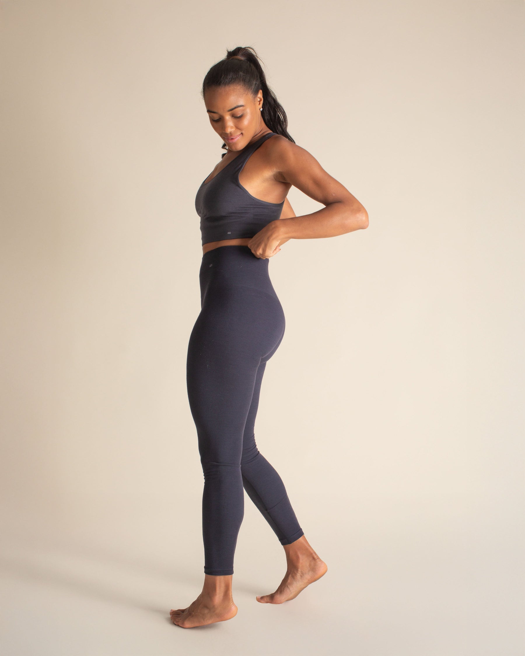 Side view of woman wearing BRANWYN Merino wool compression leggings and racerback bra.