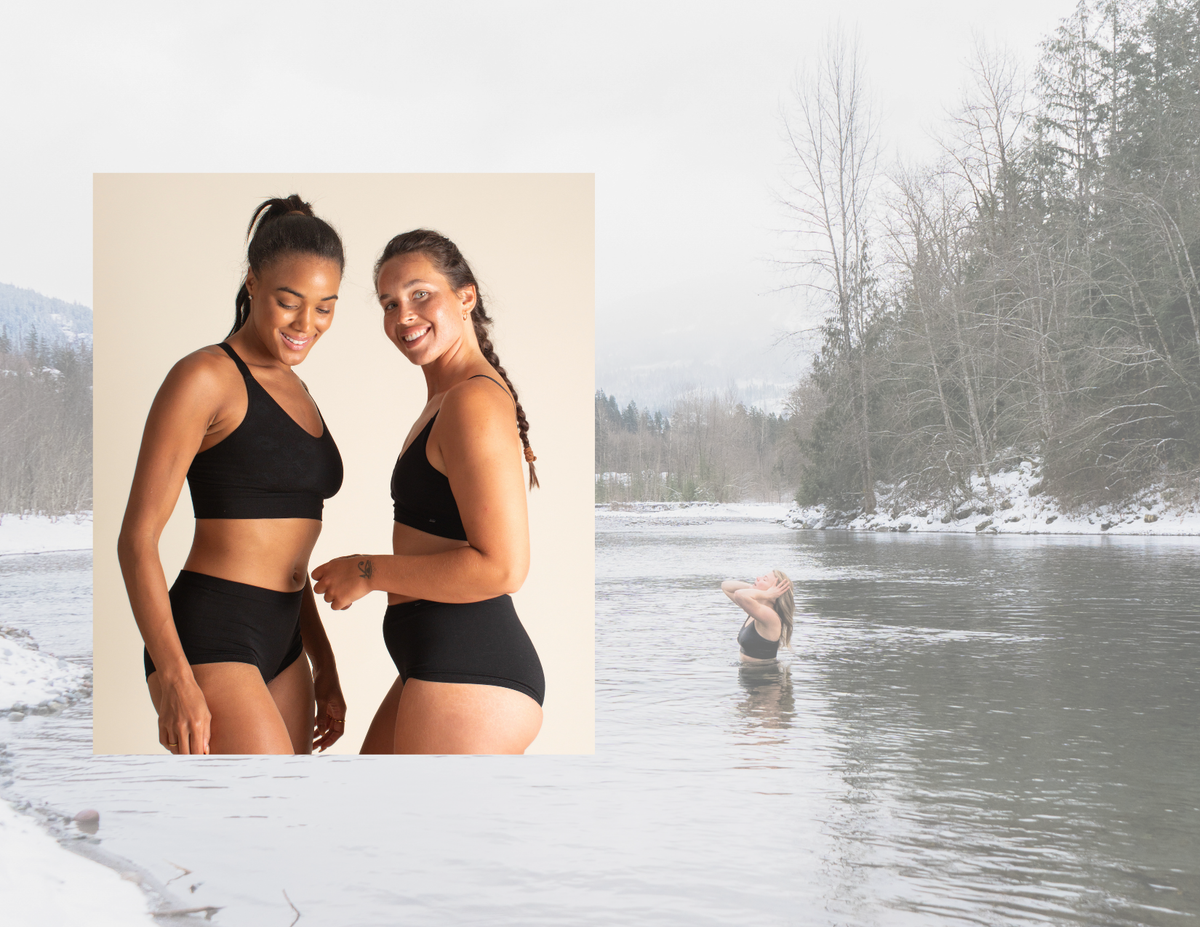 Two women in black Merino wool bras and underwear standing next to a snowy landscape with a person in the water cold dipping