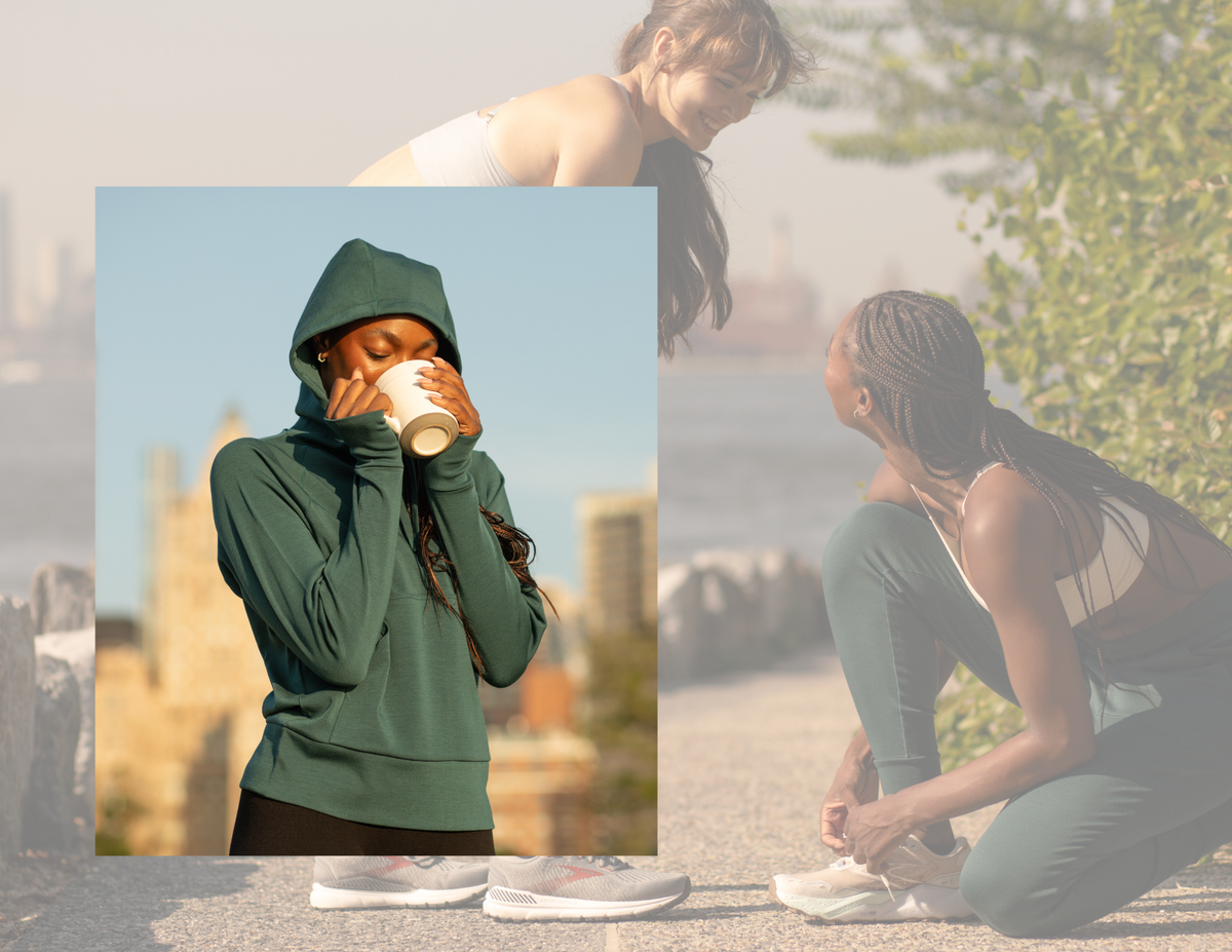 A person wearing a green hoodie is drinking from a cup with a blurred background of two people sitting on a bench.