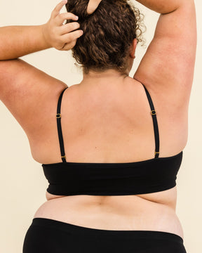 Person wearing a black bikini set against a beige background