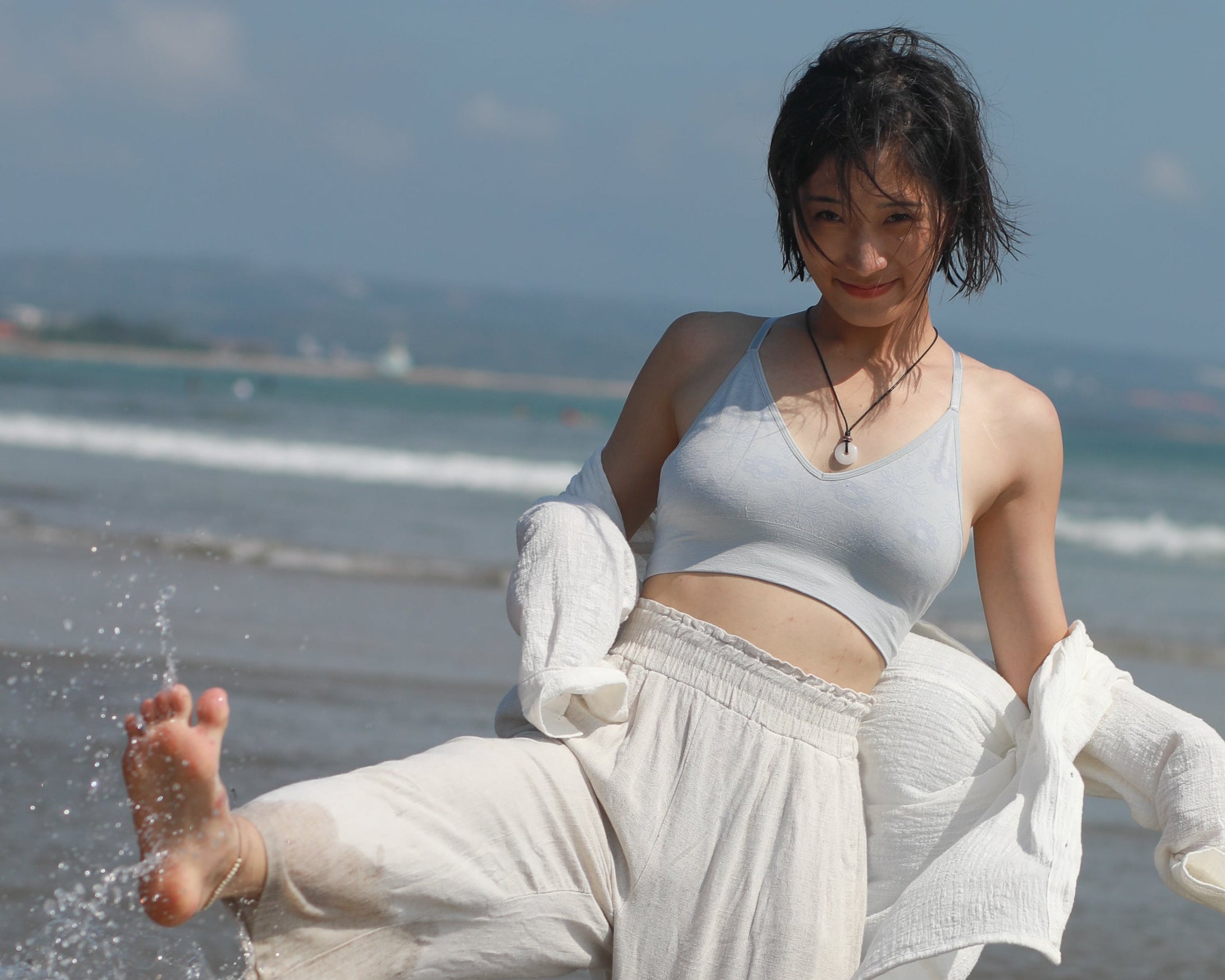 Woman in white outfit playing in water on a beach