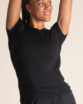 Woman stretching in soft black Merino t-shirt. A lightweight women's wool short sleeve shirt that is quick drying, odor free, and super soft.