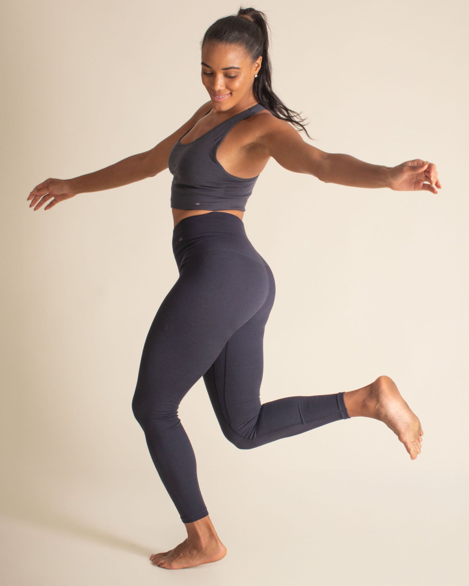 Woman jumping in BRANWYN's Essential Compressive leggings in Night Sky blue. Merino leggings for yoga, gym sessions, or as a warm base layer in for winter.