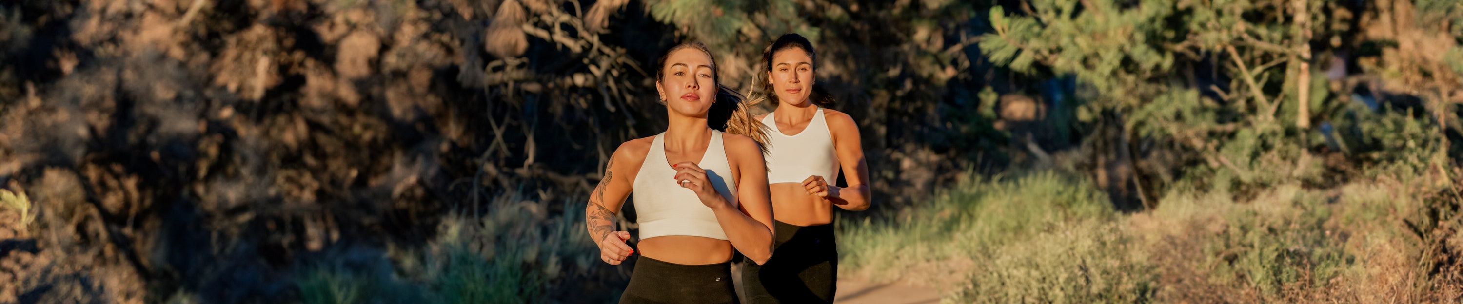 Two women running outside in BRANWYN natural white undyed seamless Merino bras and shorts