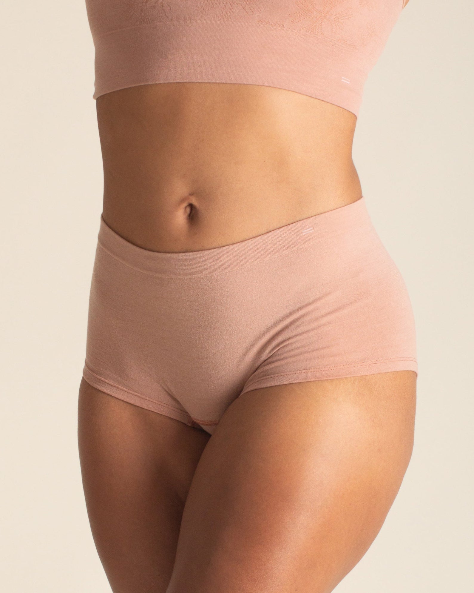 Woman wearing BRANWYN Essential Boyshort seamless Merino underwear in warm nude with matching bra. This quick drying underwear keeps you dry and fresh.
