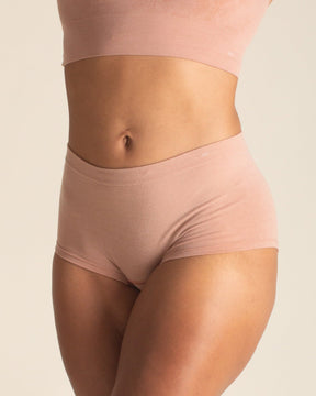 Woman wearing BRANWYN Essential Boyshort seamless Merino underwear in warm nude with matching bra. This quick drying underwear keeps you dry and fresh.